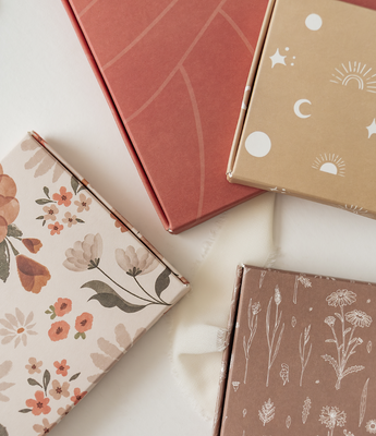 A pink box with a floral pattern and eucalyptus leaves.