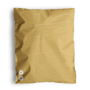 Impack.co's SALE - Tidal Amber Mailers 10" x 13" package includes a crumpled brown pillowcase with abstract white lines and two round badges in the bottom left corner, all in an eco-friendly biodegradable mailer.