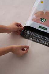 Hands sealing an impack.co SALE - Pastel Petals Mailer (10" x 13") with a zip-lock mechanism, ensuring transit protection against a beige background.