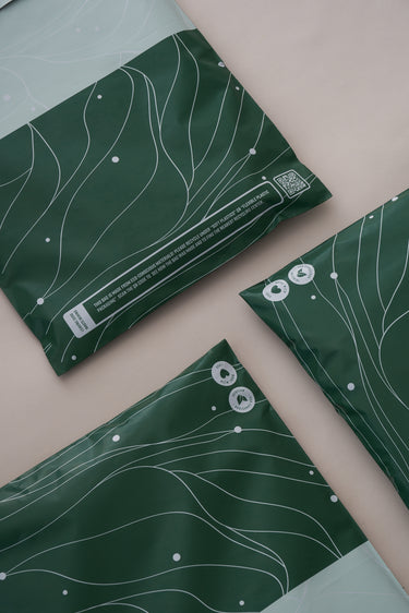 Impack.co's SALE Japanese Green Mailers, 10" x 13", feature white abstract lines and recycling symbols on a beige background. These biodegradable envelopes offer versatile, eco-friendly packaging and reliable transit protection.