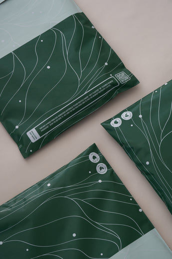 Impack.co's SALE Japanese Green Mailers, 10" x 13", feature white abstract lines and recycling symbols on a beige background. These biodegradable envelopes offer versatile, eco-friendly packaging and reliable transit protection.