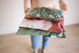 A woman is holding a bunch of Emerald Evergreen Biodegradable Mailers 10" x 13" from impack.co.