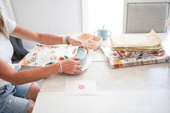 A woman is sitting at a table with Celestial Padded Paper Mailers 6" x 9" from impack.co on it, creating a brand experience.