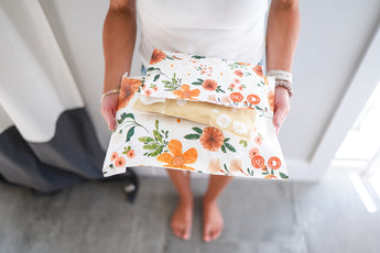 A woman is holding a bag of orange florals in Gardenlumina Padded Paper Mailers 10" x 13" from impack.co.