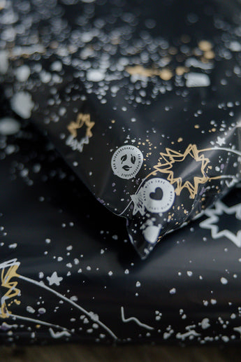 A close-up of the impack.co Midnight Galaxy Mailers, featuring a celestial design adorned with white and gold star patterns and circular logos on a dark backdrop.