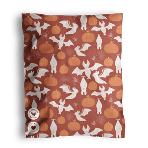 The impack.co SALE - Halloween Bats Mailers (10" x 13" US) feature white bats, light orange pumpkins, and spider webs on a rust background—ideal for festive, biodegradable Halloween shipping.