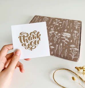 A person holding a thank you card next to an impack.co ABC Box Wildflower 7" x 8" - Large.