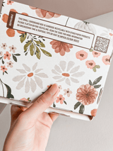 A hand holding a stylish ABC Box Gardenlumina 4.8" x 6" - Medium with floral packaging from impack.co.