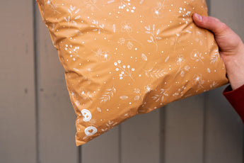 A person holding a Floral 2D Chestnut Biodegradable Mailer 14.5" x 19" from impack.co.