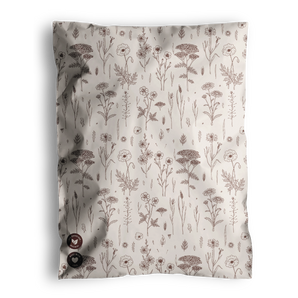 The Wildflower Biodegradable Mailers from impack.co feature a crumpled fabric design adorned with a pattern of brown flowers and plants on a white background, exuding an eco-friendly charm. Tiny buttons in the bottom left corner subtly echo the intricate details commonly seen on biodegradable mailers.