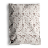 A cream-colored blanket featuring an elegant pattern of brown floral and botanical designs is delivered in Wildflower Biodegradable Mailers by impack.co, combining style with eco-friendly packaging.