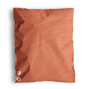 The SALE - Natural Cedar Leaf Biodegradable Mailers by impack.co showcases a delicate Cedar Leaf design on its orange pouch. It is accented with two round symbols at the bottom left corner. These mailers offer robust protection for their contents and emphasize an eco-friendly approach.