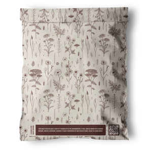 The Wildflower Biodegradable Mailers 12" x 15.5" by impack.co offer sealed, recyclable floral packaging with brown illustrations on cream and a boxed sustainability message beside a QR code—ideal for plastic-free packing.