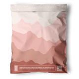 The impack.co Mountain Clay Mailers 10"x13" are sealed, resealable mailers with a pink and mauve abstract mountain design, a white QR code, and sustainability text—ideal for eco-friendly packaging needs.