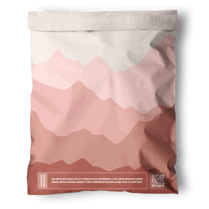 The impack.co Mountain Clay Mailers 10"x13" are sealed, resealable mailers with a pink and mauve abstract mountain design, a white QR code, and sustainability text—ideal for eco-friendly packaging needs.