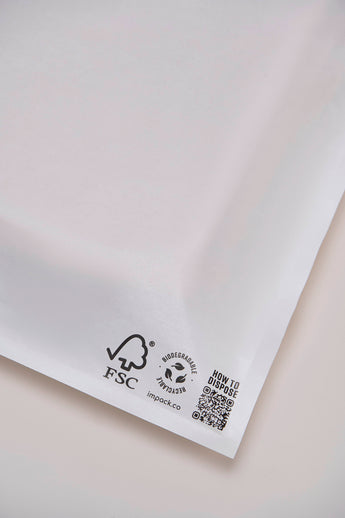 Close-up of a Glassine Bag by impack.co, measuring 14.1" x 18.6". This white biodegradable envelope is perfect for shipping t-shirts and features FSC and recycling symbols with a QR code in the bottom right corner on a plain background.