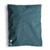 A Space Blue Leaf bed pillow with a leaf pattern design and two decorative buttons, resting on a similarly patterned impack.co recyclable surface.