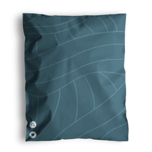A Space Blue Leaf bed pillow with a leaf pattern design and two decorative buttons, resting on a similarly patterned impack.co recyclable surface.