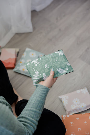 A woman is sitting on the floor with a bunch of Biodegradable Mailers 6" x 9" in front of her.