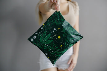 A woman is holding up a Midnight Lush Mailers 10" x 13" bag with stars on it made by impack.co.