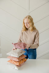 A woman is putting biodegradable mailer bags 10" x 13" from impack.co on a table.