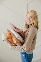 A girl holding a stack of biodegradable mailer bags 10" x 13" from impack.co in front of a white wall.